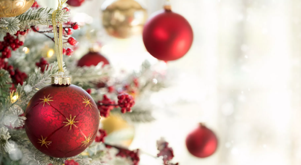 Dekorierte Weihnachtsbaumkugeln in Rot und Gold an einem geschmückten Weihnachtsbaum.