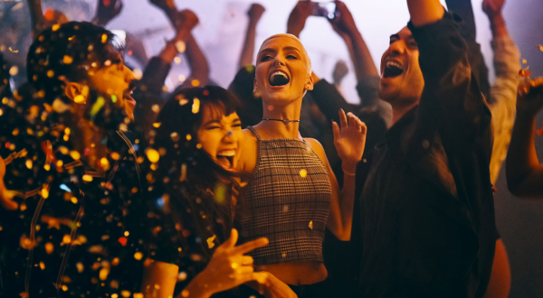 Junge Menschen feiern zusammen auf einer Party, umgeben von Konfetti und guter Stimmung.