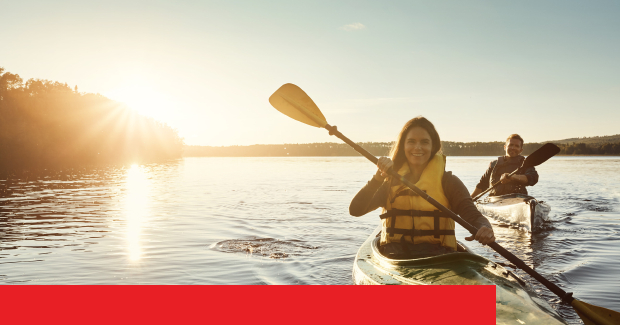 Zwei Menschen im Kajak bei Sonnenuntergang auf einem ruhigen Gewässer, beide tragen Schwimmwesten.