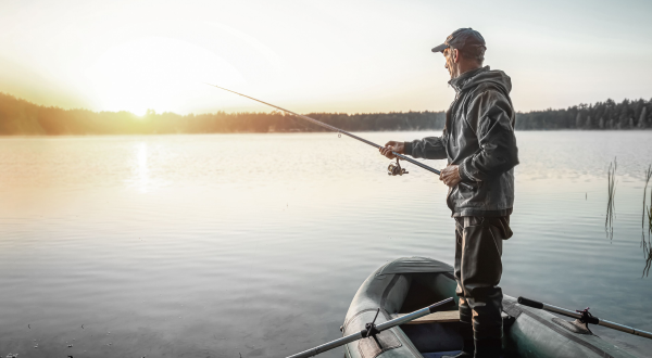 Angler beim Fischen in einem Boot am See bei Sonnenaufgang, tolle Atmosphäre und Ruhe.
